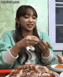 a woman is sitting at a table eating meat .