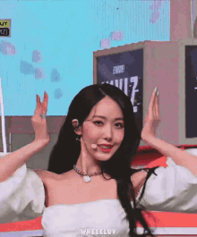 a woman wearing a white off the shoulder top and a necklace with the word wheeluv on the bottom right