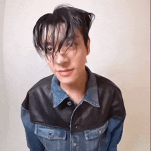 a young man with wet hair wearing a denim jacket and a leather jacket .
