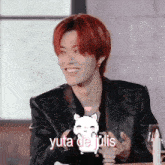 a man with red hair is sitting at a table with a cat and the words yuta de julis above him
