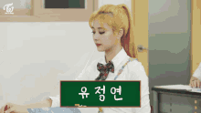 a girl in a ponytail sits in front of a chalkboard with korean writing on it