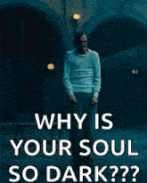 a man in a white shirt is standing in a dark room with the words why is your soul so dark .
