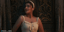 a woman in a white dress is standing in front of a door with pranay_varma written on the bottom