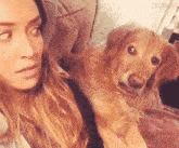 a woman is sitting on a couch holding a dog that is looking at the camera .