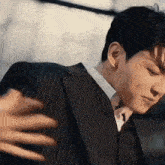 a man in a suit and tie is hugging another man 's hand .