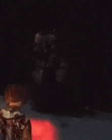 a person is standing in the dark in front of a red fireball .