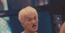 a man with blonde hair is making a funny face in front of a sign that says rfg