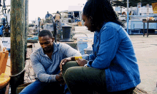 a man and a woman sit on a bench with a sign that says man on it