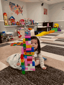 a little girl sits on the floor playing with a stack of lego blocks with the numbers 1 through 6 on them