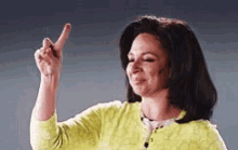 a woman in a yellow sweater is pointing up .
