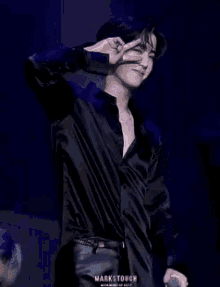 a man in a black shirt and leather pants is giving a peace sign .
