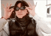 a man wearing sunglasses and a black vest is making a funny face .