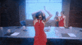 a woman in a red dress is dancing in front of a conference room table