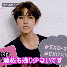 a young man is holding a sign that says `` exo - s '' in a foreign language .