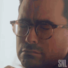 a close up of a man wearing glasses with snl written on the bottom