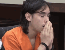 a man covering his mouth with his hands in a chair