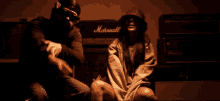 a man and woman are sitting in front of a marshall amplifier