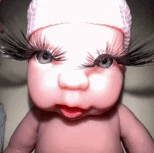 a baby doll with long eyelashes and a hat on