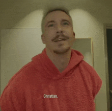 a man wearing a red hoodie with christian stop written on it