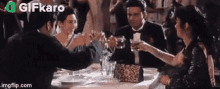 a group of people are sitting at a table toasting with glasses .