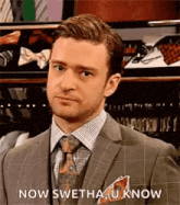 a man in a suit and tie is standing in front of a closet and says `` now swetha u know '' .