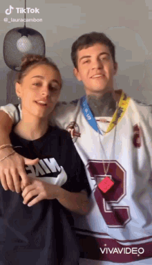 a man and a woman are posing for a picture and the woman is wearing a nike shirt