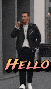 a man wearing a leather jacket is standing in front of a sign that says hello