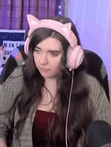 a woman wearing pink headphones with cat ears is sitting in front of a microphone .