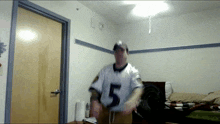 a man wearing a number 5 jersey stands in a room