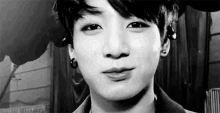 a black and white photo of a young man 's face with a smile on his face .