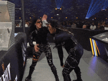 two women are wrestling in front of a sign that says w