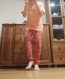 a child wearing a shirt that says " i love you " stands in front of a wooden dresser