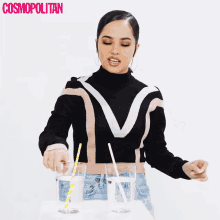 a woman in a black and tan sweater is pouring water into a glass with a straw