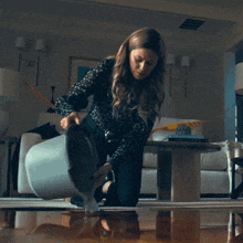 a woman pours water from a bucket into a flooded floor