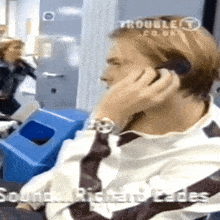 a man talking on a cell phone with troublet.co.uk written on the bottom right