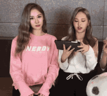 a girl wearing a pink nerd sweatshirt looks at a tablet