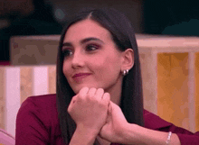 a woman in a red shirt is smiling with her hands folded on her chin
