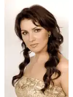 a woman with long dark hair is wearing a strapless gold dress