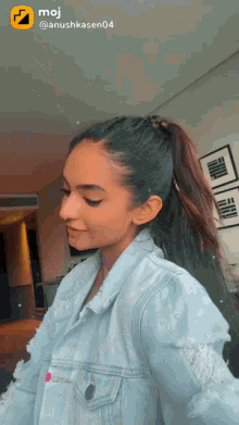 a woman wearing a denim jacket and a ponytail has a moji icon on her face