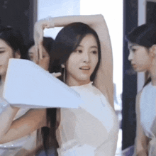a woman in a white dress is holding a piece of paper over her head