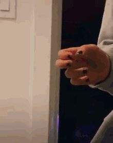 a close up of a person 's hand with black nails holding a door handle .