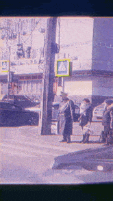 a man in a black coat stands in front of a crosswalk sign that says a on it