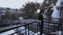 a woman standing on a balcony with the words made in animatica on the bottom right