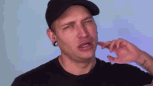 a man wearing a hat and a black shirt has a tattoo on his arm