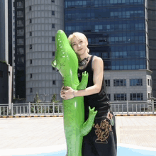 a man is holding a green inflatable crocodile in front of a building
