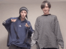 two people are standing next to each other wearing striped shirts and hats