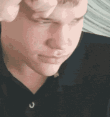 a close up of a man 's face with his eyes closed and his hand on his head .