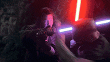 two men are fighting with lightsabers in a dark room