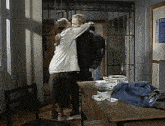 a man and a woman are hugging in a room with a prison cell in the background