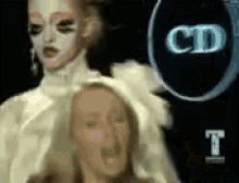a close up of a doll 's face with a cd logo in the background .